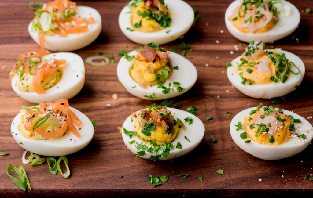 An egg flight on a wooden board as part of a roundup on thanksgiving appetizers