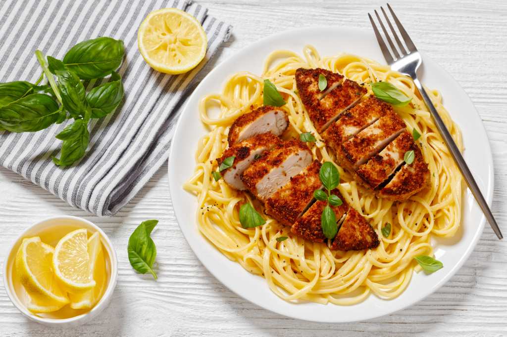 pumpkin seed crusted chicken over lemon butter pasta on white plate