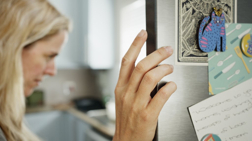 mature woman checking fridge temperature to boost ozempic injection effectiveness