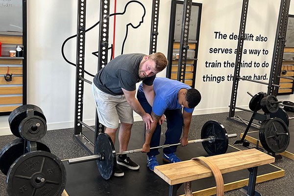 andrew lewis demonstrates the position of the elbow relative to the knee in the deadlift