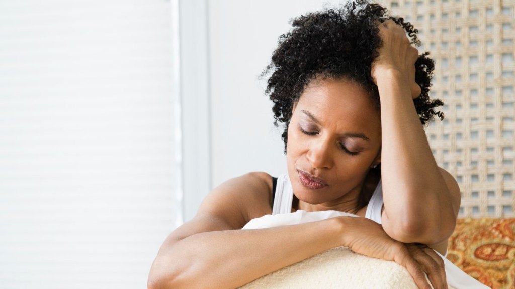 Mid adult woman sitting on the bed and suffering from a headache