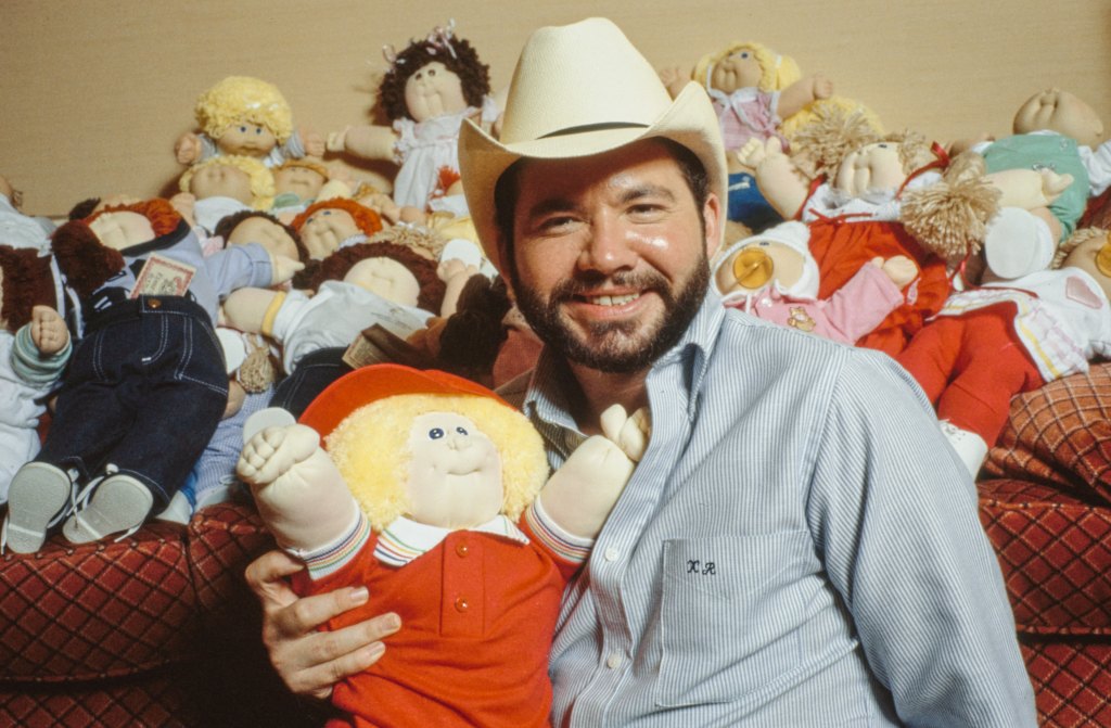 Cabbage Patch Doll Creator Xavier Roberts, sits amongst a group of Cabbage Patch Kids at a London hotel ahead of the toys being introduced into the U.K. Christmas market in London, U.K., on Thursday, December 8, 1983. 