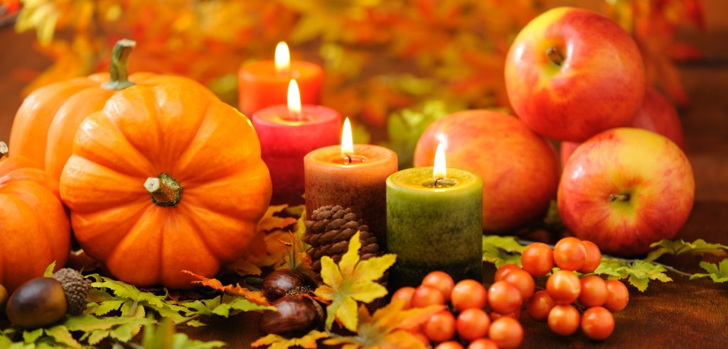 Table centerpiece ideas: candlescape centerpiece of autumn-hued votive candles and gourds on tabletop