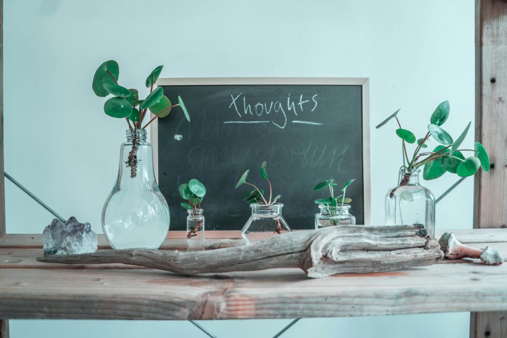 glass vases in front of chalkboard with 'thoughts' written on it