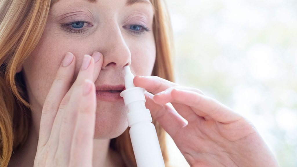 woman using nasal decongestant spray