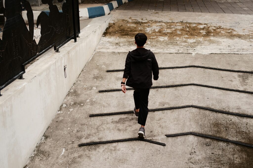 A man in a black suit walking purposefully up a concrete slope