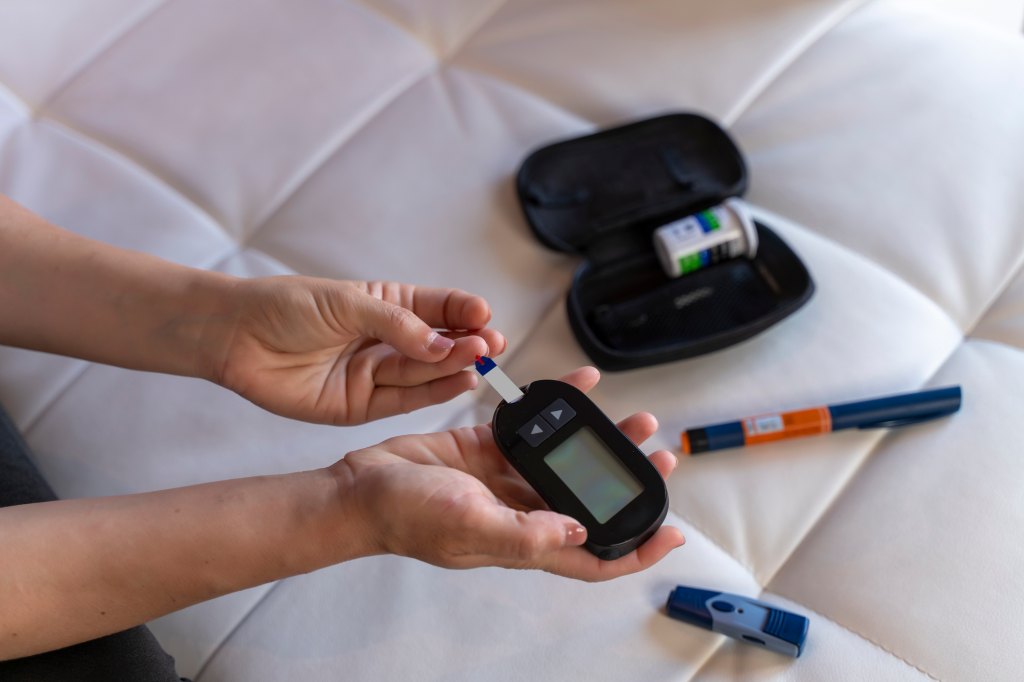 woman with prediabetes checking blood sugar levels with a glucose meter at home