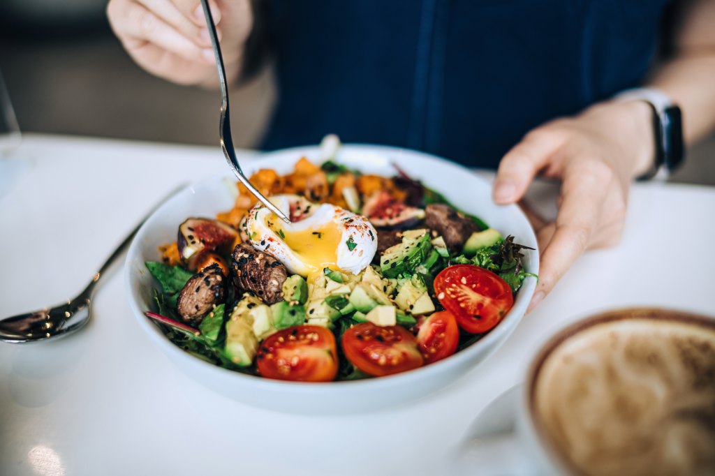 close up of woman eating a dish of high-fiber, high-protein salad as part of her prediabetes self-care routine