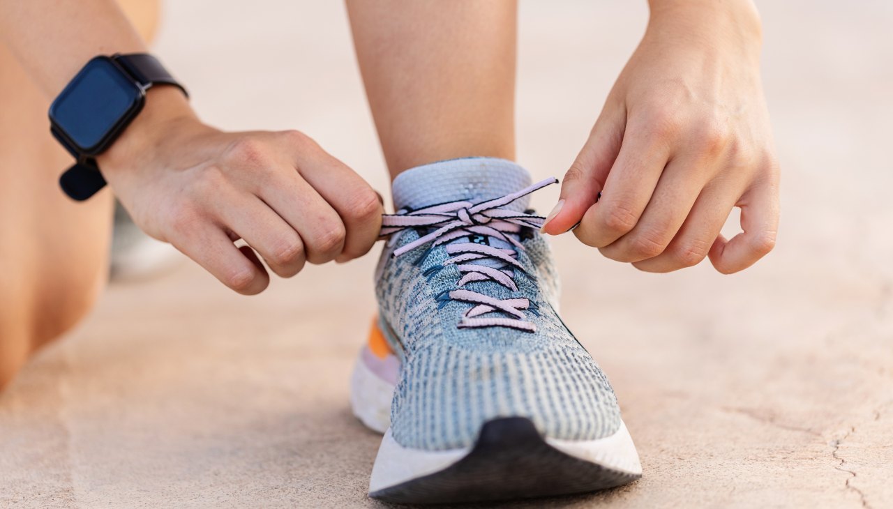 Close-up view of female jogger hands tying laces of her sport shoes before running exercise routine. Motivation, healthy lifestyle and fitness concept.