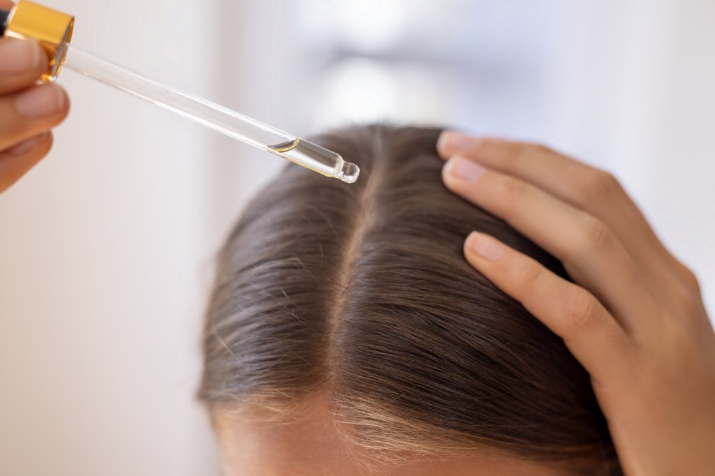 woman applying hair serum to scalp 