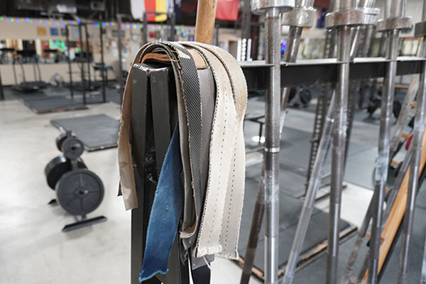 pile of straps hanging from a barbell rack in the gym