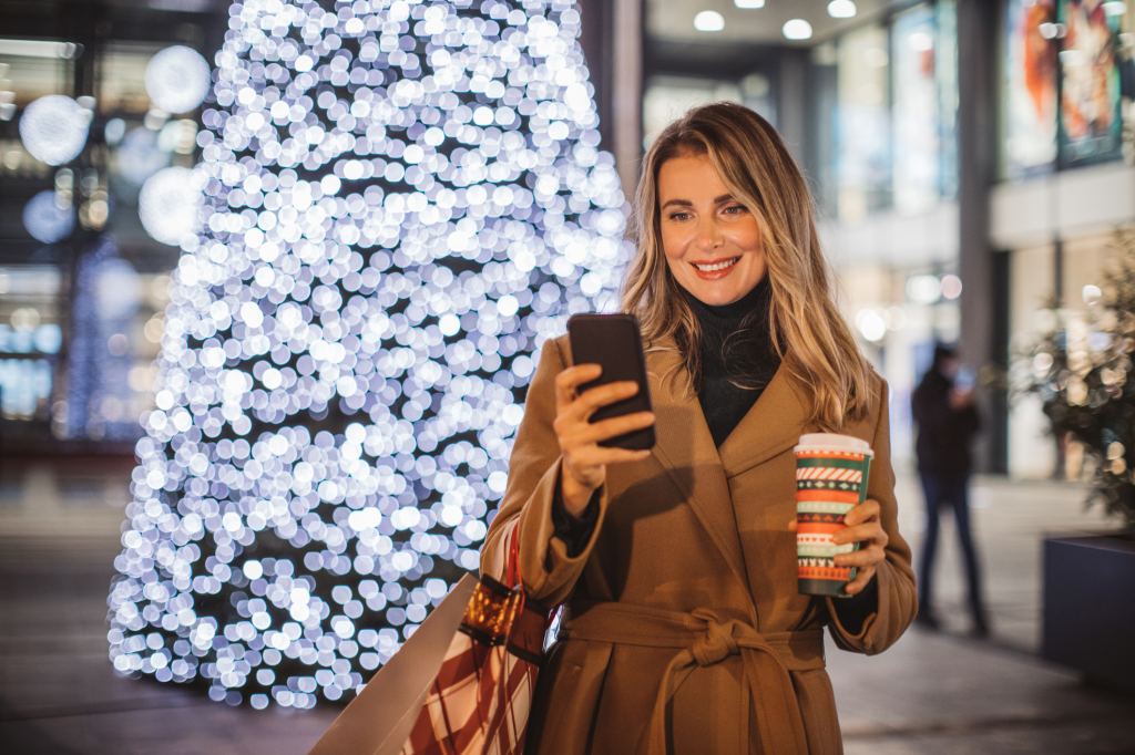 mature woman playing starbucks for life game on phone with coffee outside