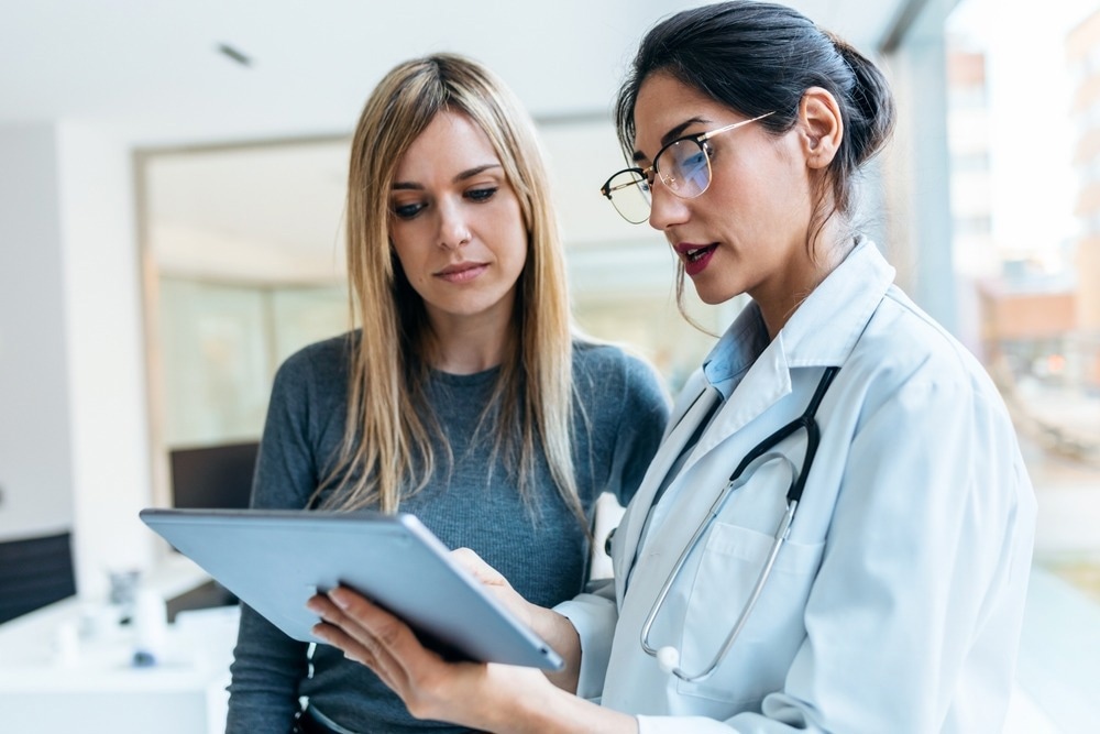 Female doctor talking while explaining medical treatment with digital tablet to patient in the consultation