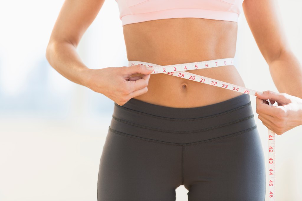 trim woman measures her waistline