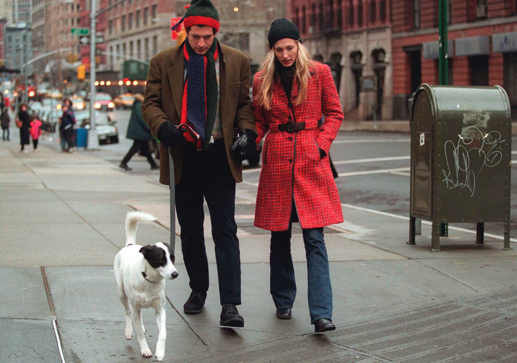 Carolyn Bessette Kennedy walking her dog in a red plaid coat with John F. Kennedy Jr.