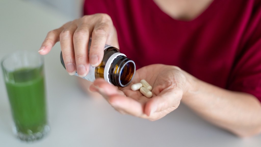 A close-up of a woman placing D-mannose pills in her palm