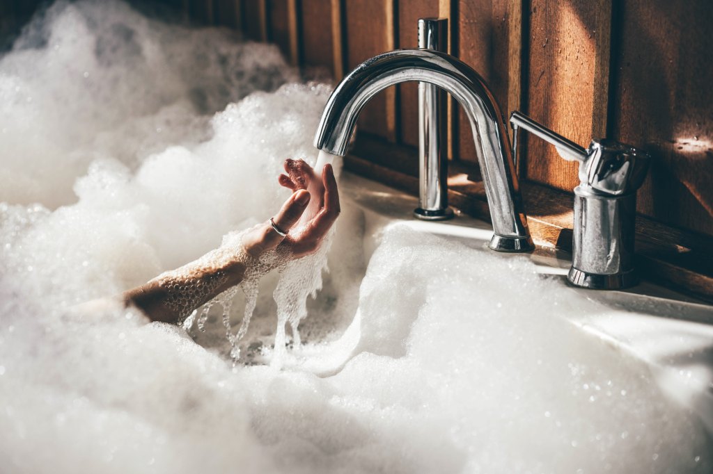 woman holding hands underwater in a warm bath to lower blood pressure