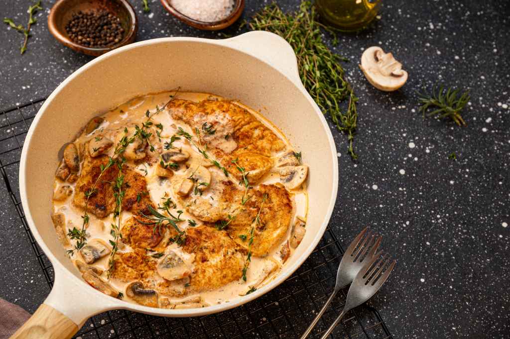 cooking champagne chicken in pan with mushroom cream sauce