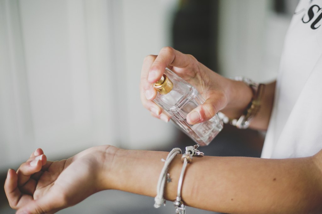 woman spraying perfume on wrist