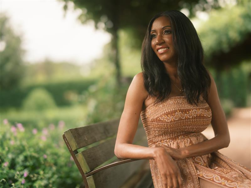 Shon Lowe looks peaceful and joyful as she sits on a bench outdoors gazes out