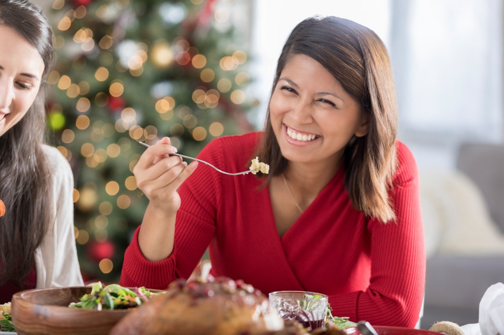 happy woman eating holiday food during Christmas dinner while on Ozempic