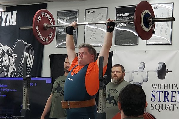 lifter locks out a heavy press at a meet