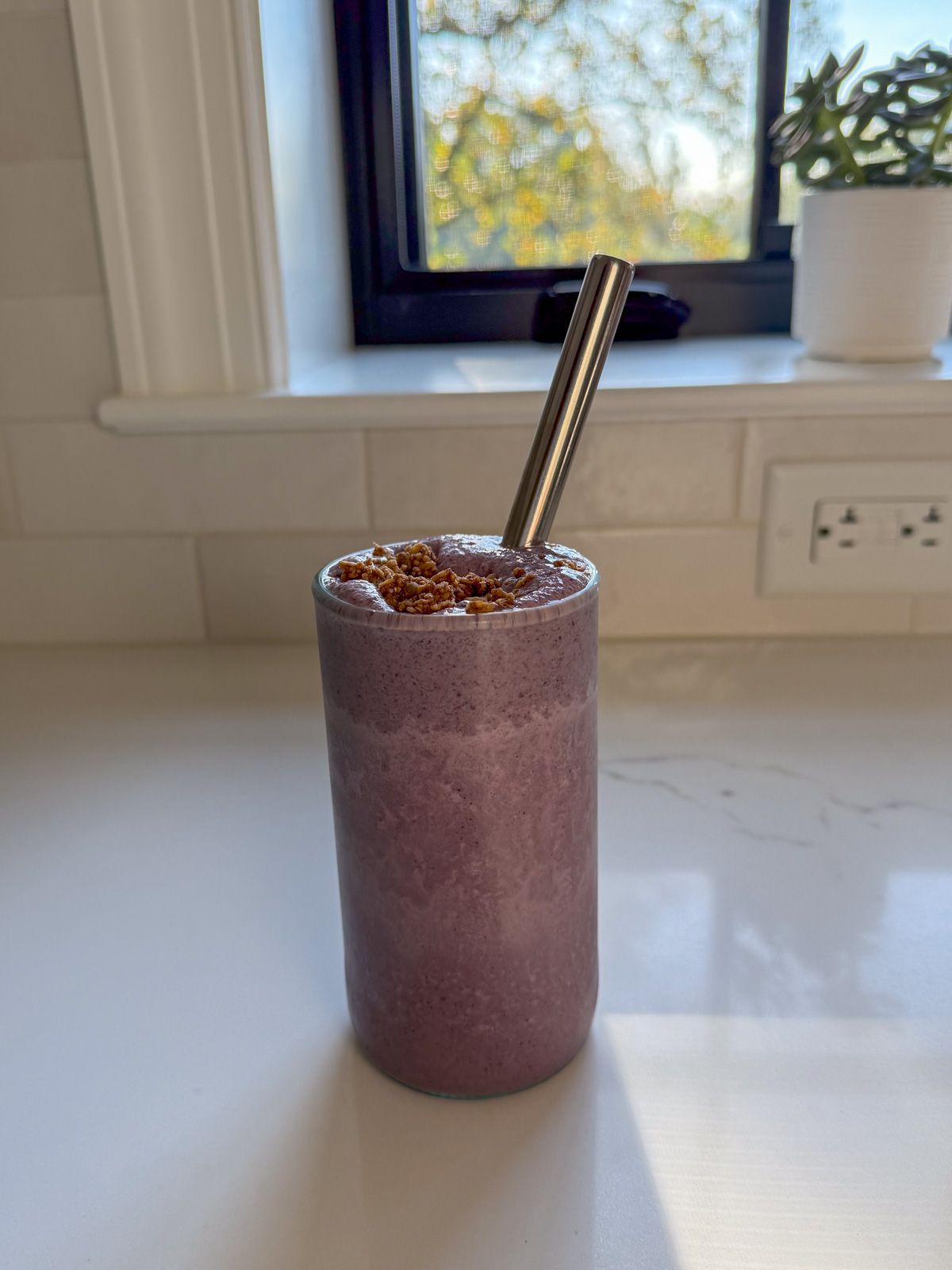 superfood smoothie in clear glass with stainless steel straw