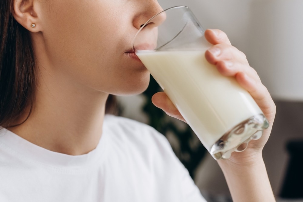 Cropped shot healthy young woman drinking milk with calcium for strong bone at home.