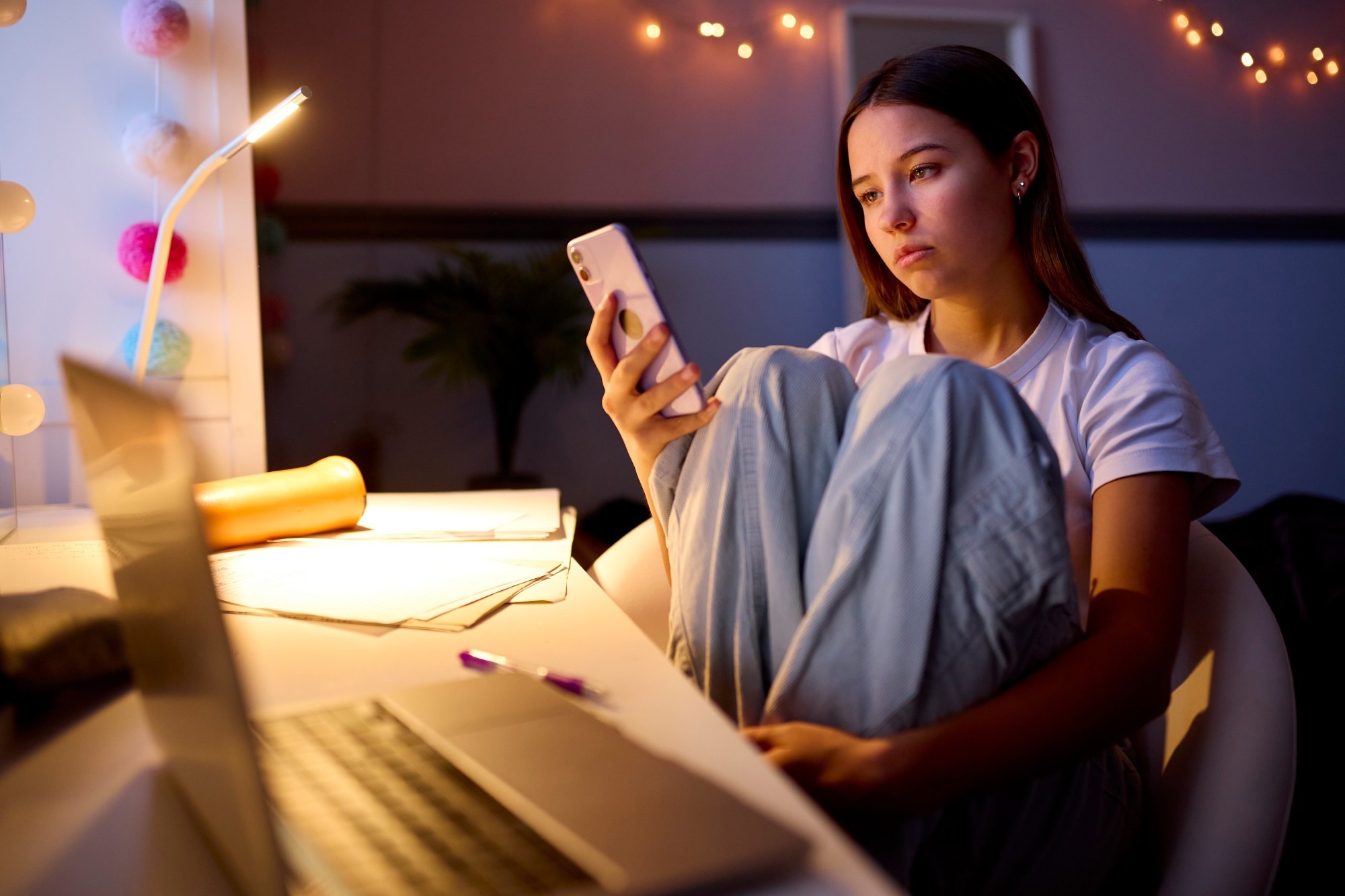 Worried Teenage Girl Sitting At Desk In Bedroom.