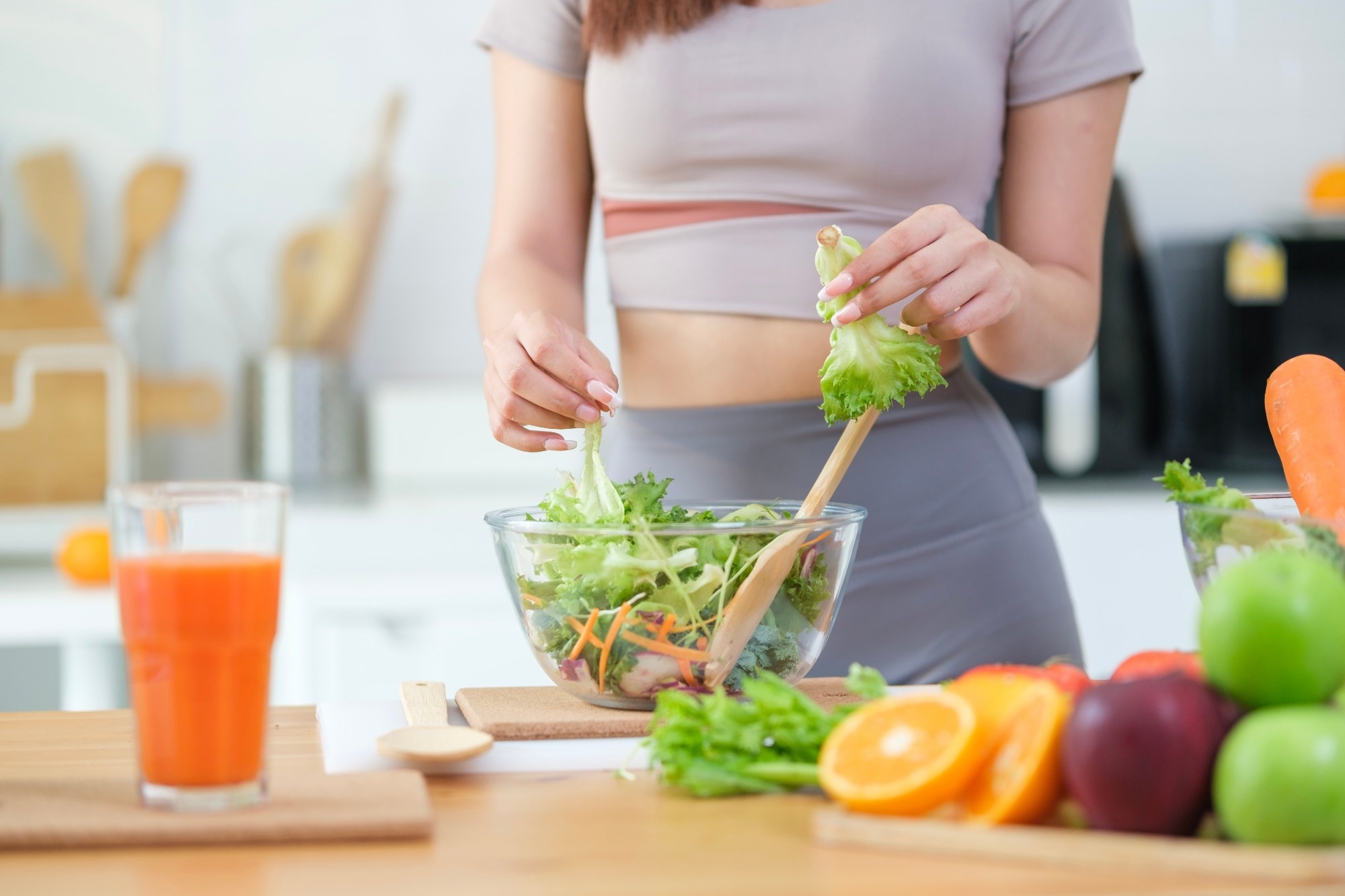 Woman preparing a healthy vegetables salad in a kitchen with fresh ingredients.