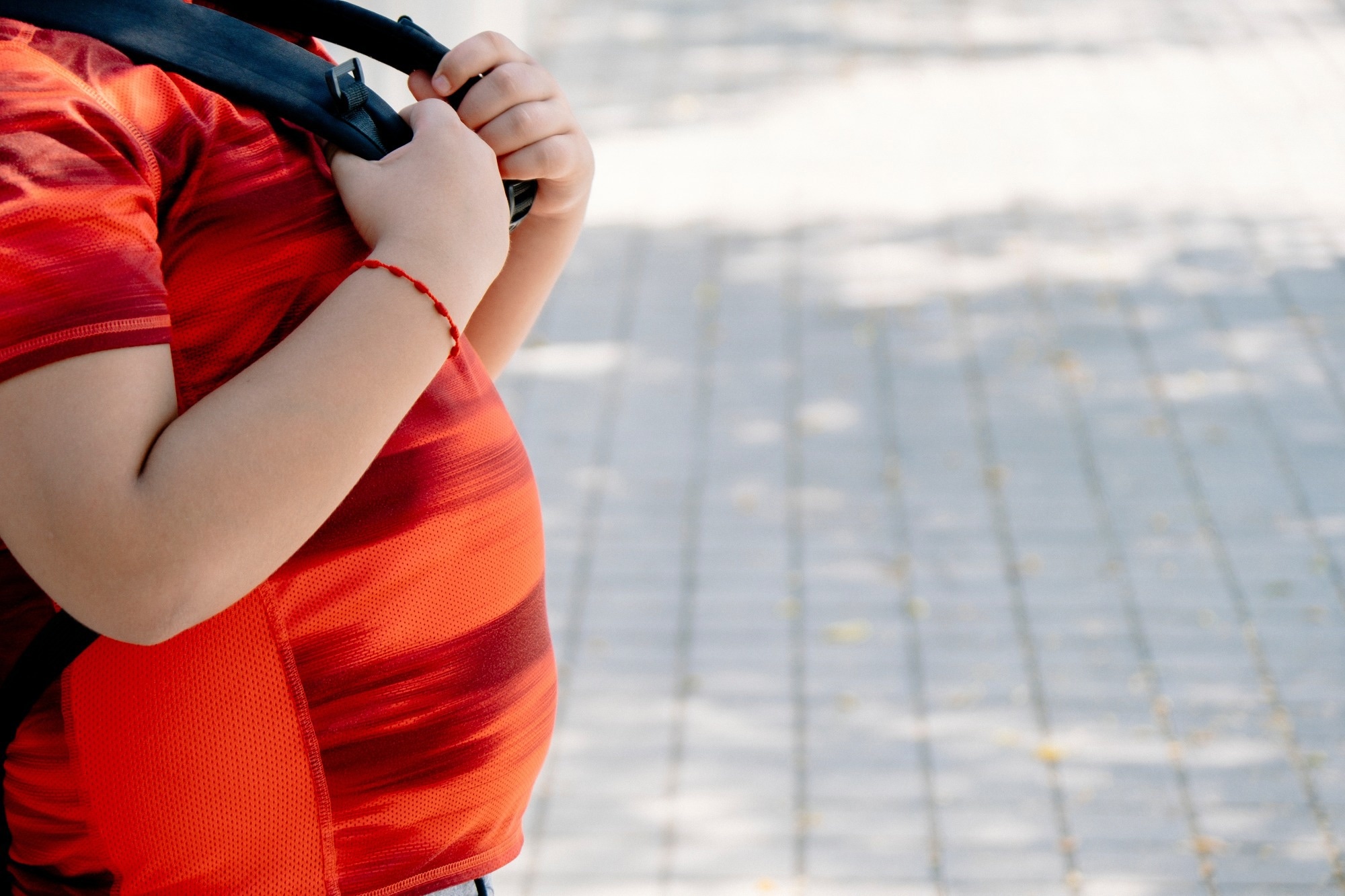 Childhood obesity concept. Boy with school bag with big belly.