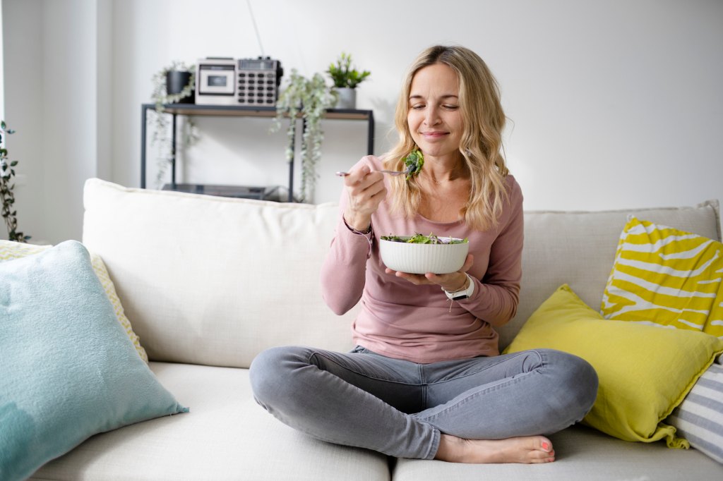 Woman eats a fiber-rich salad to stay healthy and slim.