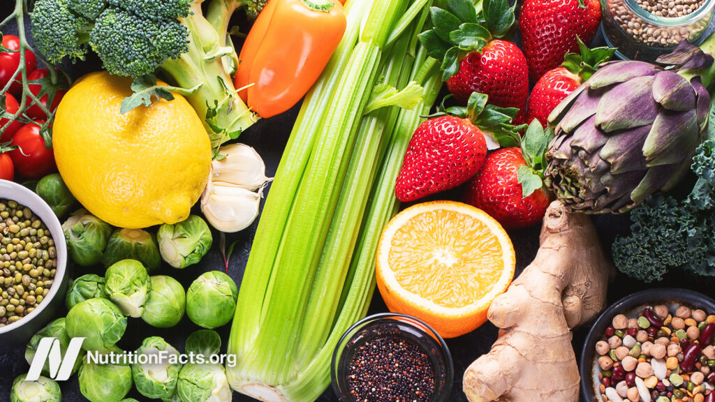 An assortment of colorful fruits, vegetables, and legumes on a flat surface