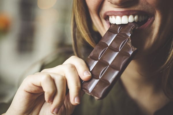 woman biting chocolate bar | Facts About Chocolate