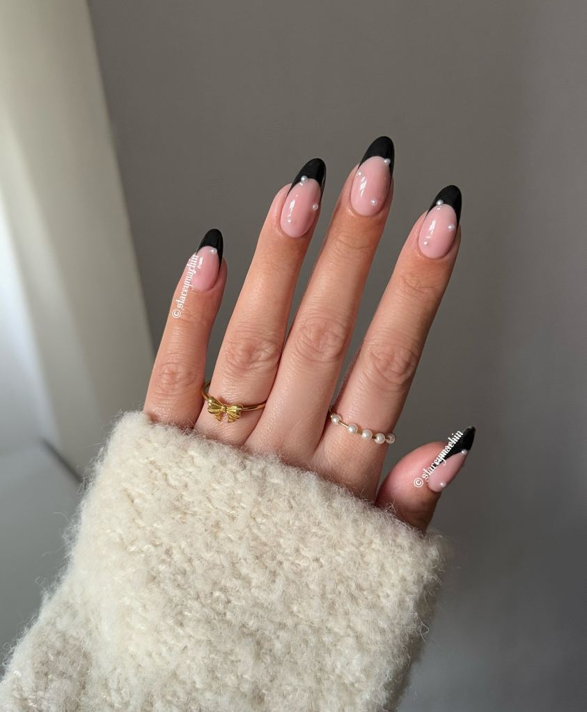 Black French tip nail design with pearl accents