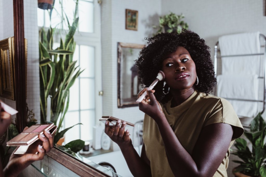 woman applying makeup in the mirror