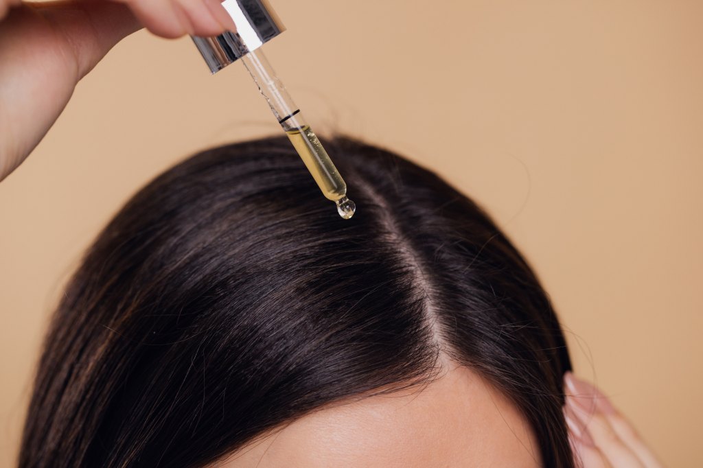 woman putting hair serum on scalp