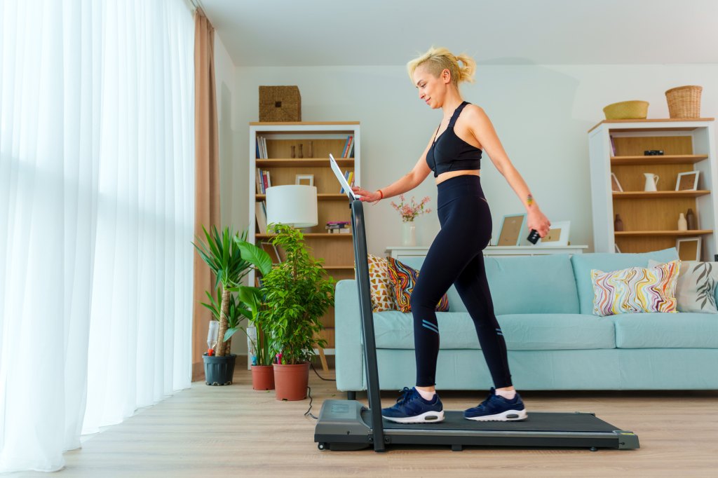 Woman walks on a walking pad in her living room to get healthy and lose weight