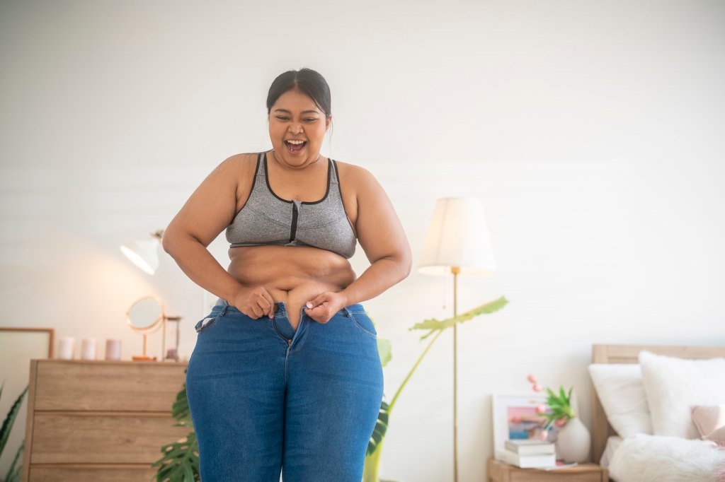 Woman celebrates fitting into smaller jeans, despite still having some excess skin, following a major weight loss success.