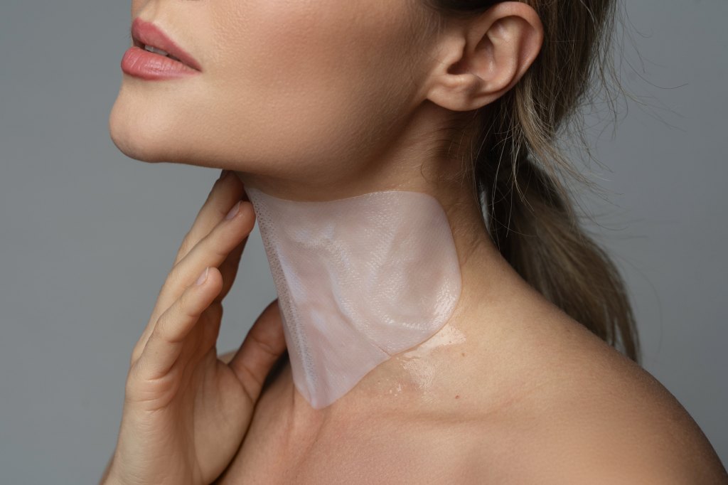 Woman wears a therapeutic neck mask to firm saggy skin.