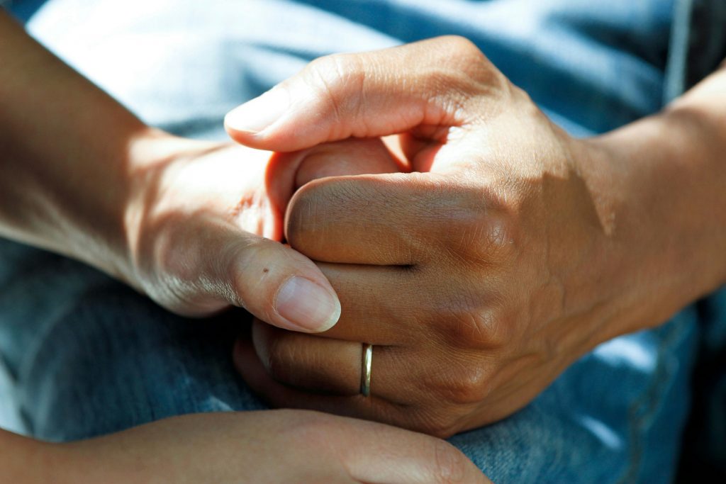 One person seemingly comforting another by holding their hand