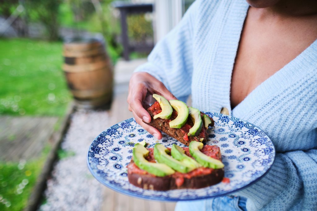 Healthy woman eats avocado toast.